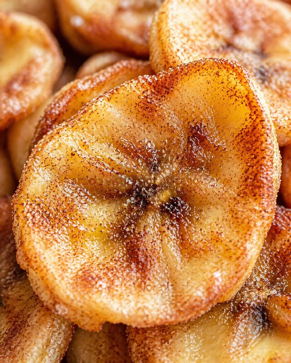 Close-up of golden cinnamon-sugar fried banana fritters with crisp edges.