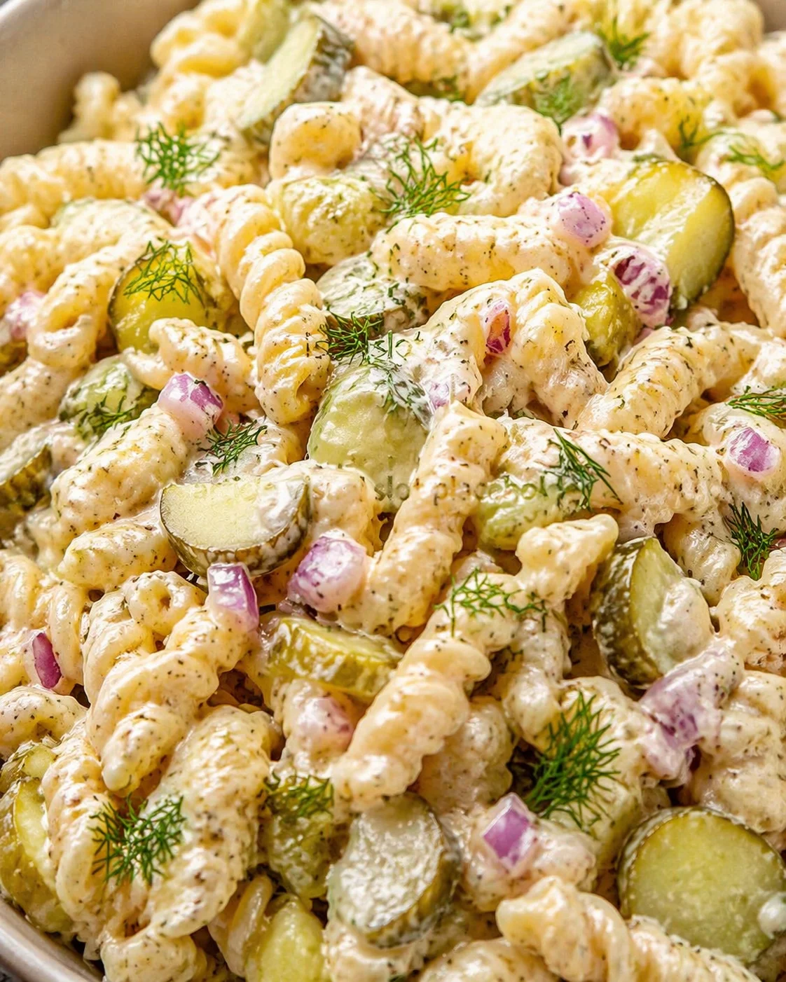 close-up of creamy dill pasta salad with rotini, cucumber, red onion, and dill
