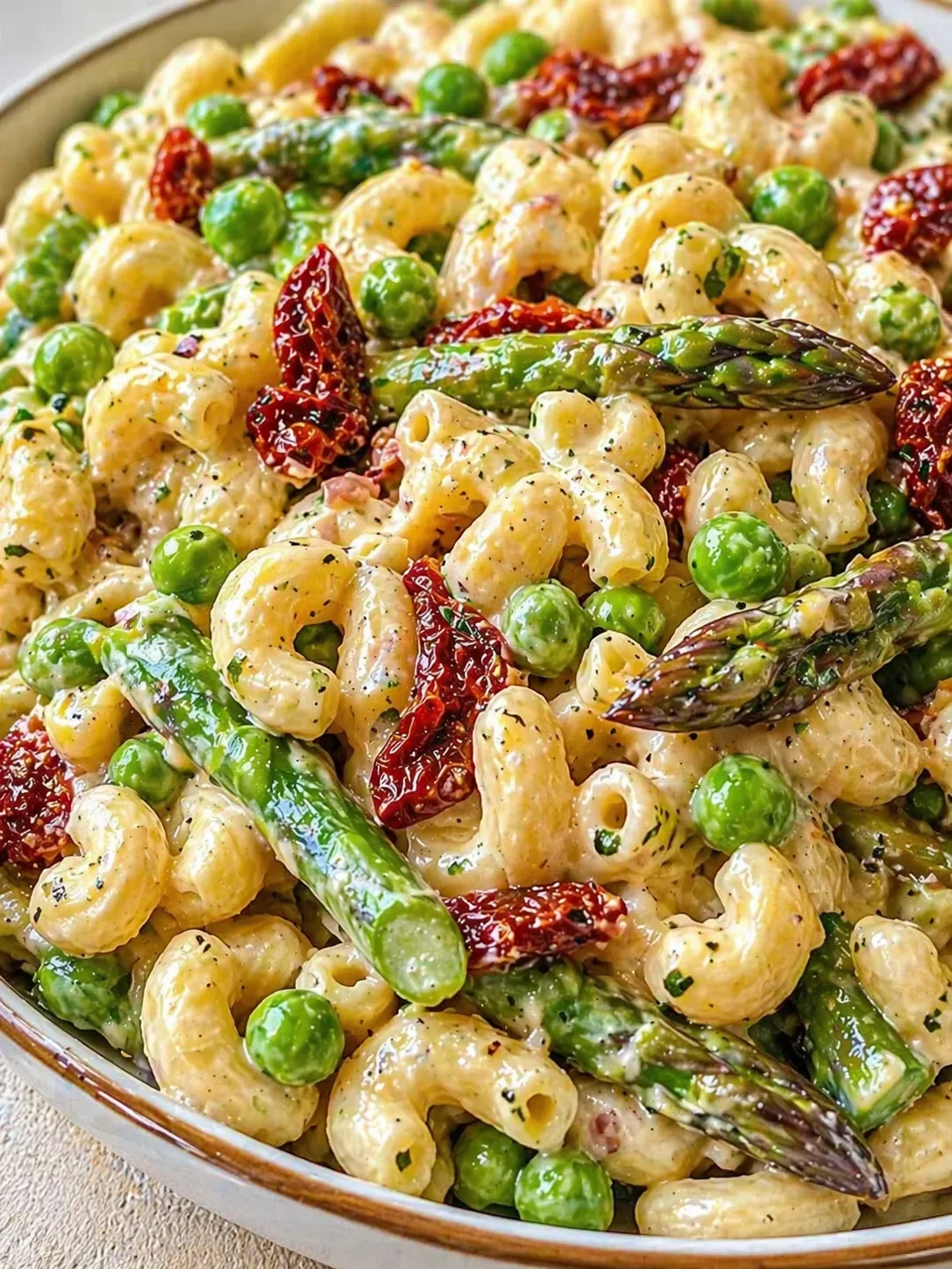 Creamy pasta with cavatappi shells, peas, asparagus, and sun-dried tomatoes in herb sauce.
