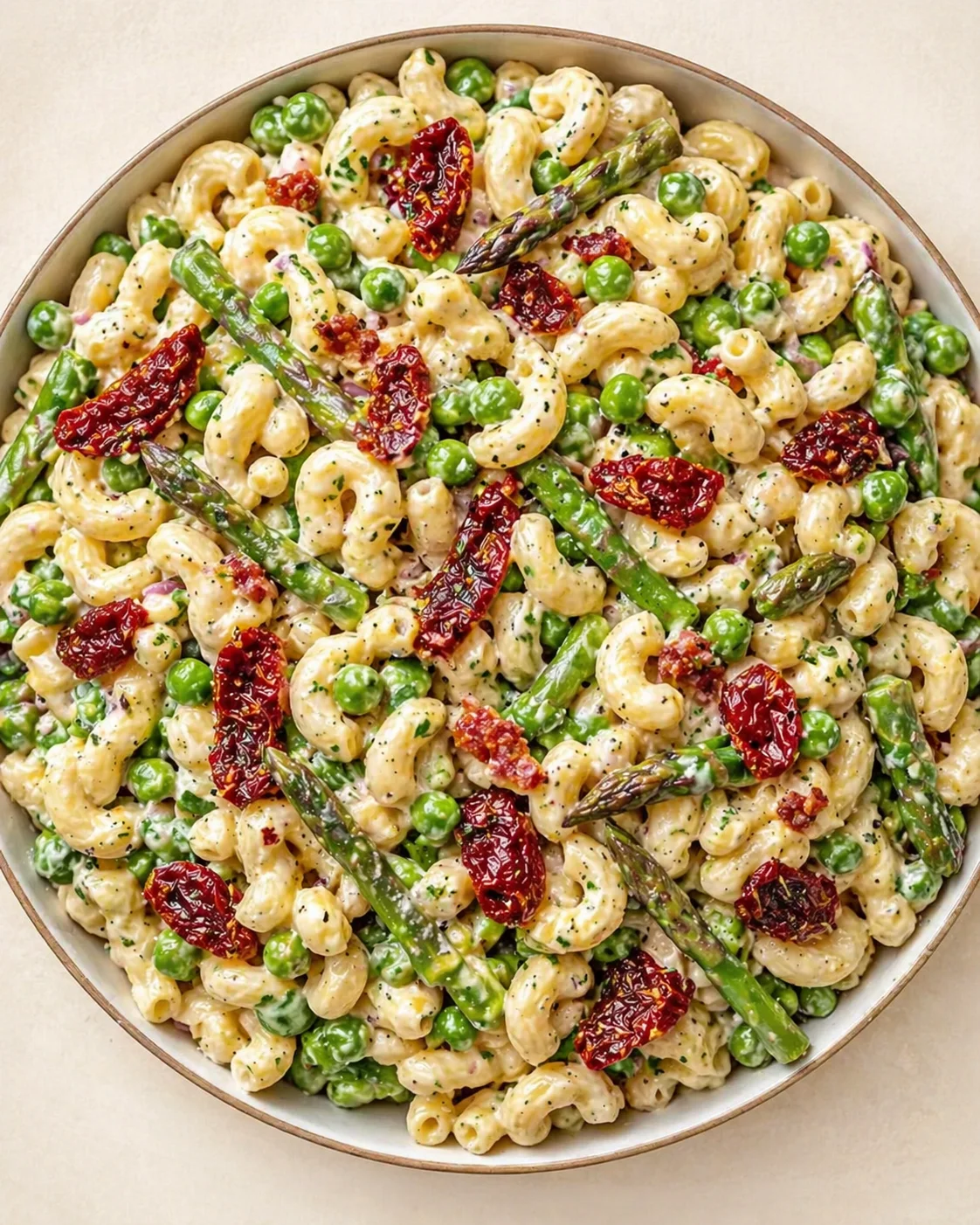 Creamy cavatappi pasta with peas and asparagus in a round bowl.