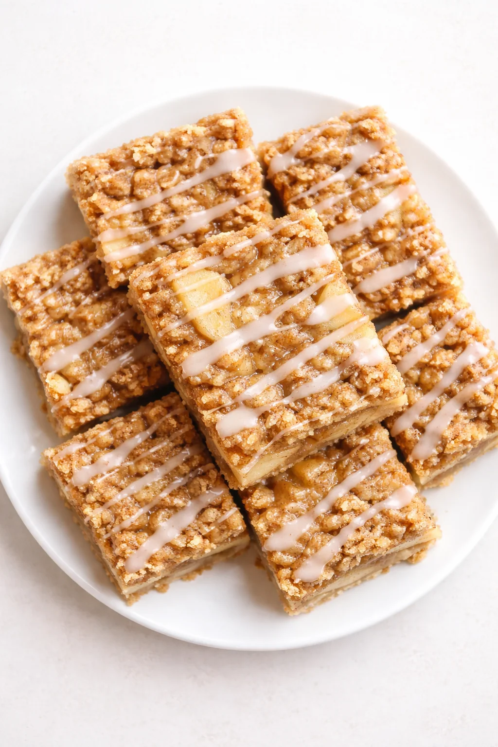 White plate holds crumbly oat bars drizzled with light icing