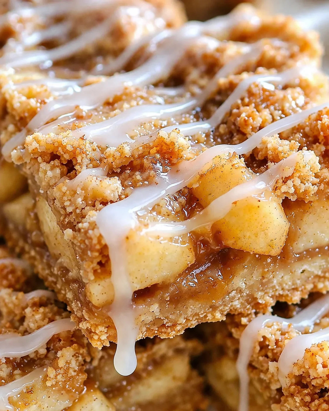 Close-up of glazed apple crumble bars with white icing drizzle.
