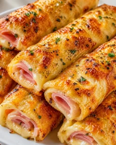 golden ham and cheese-filled bread rolls on a white plate