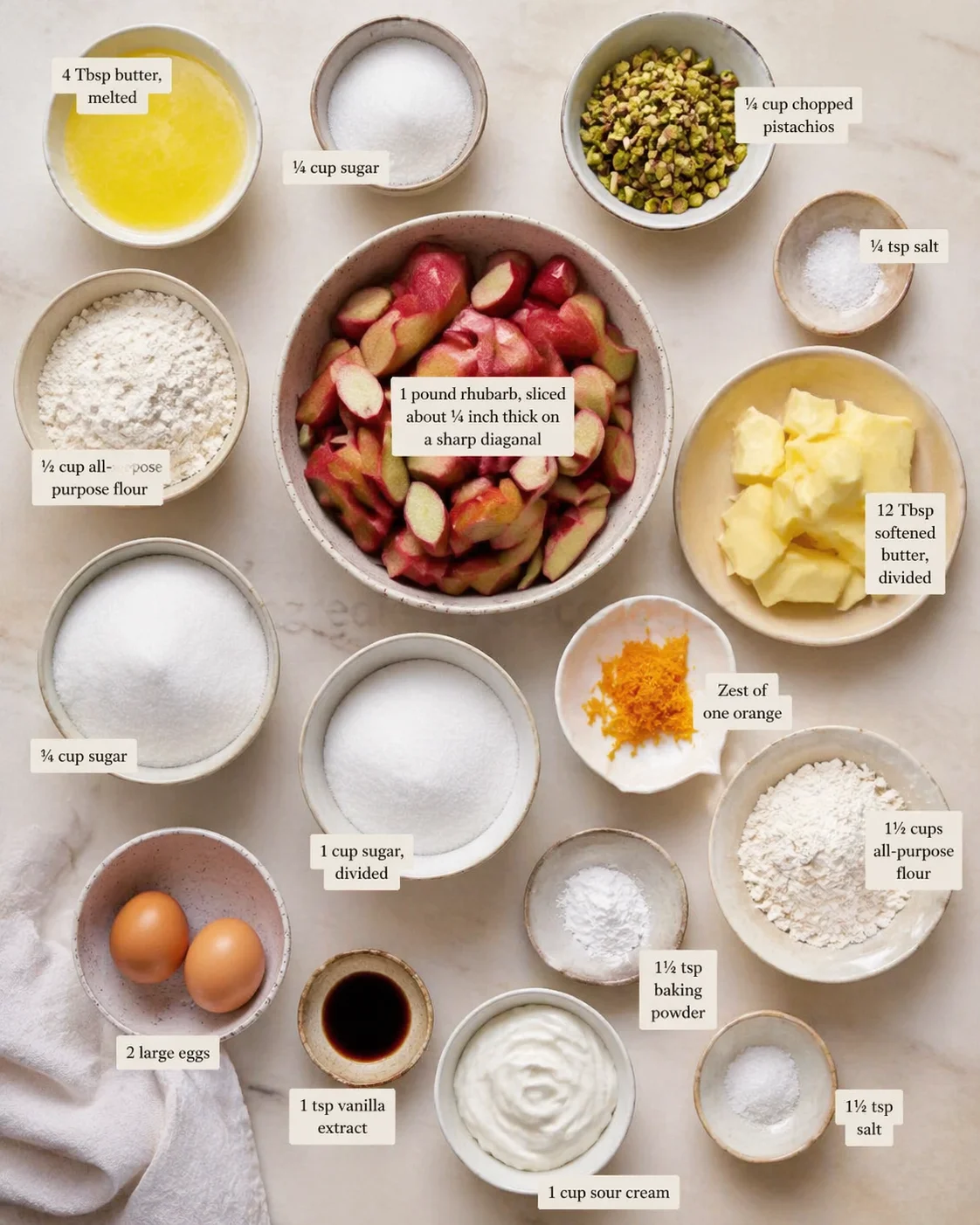 Overhead view of labeled baking ingredients arranged around a central bowl of rhubarb slices.