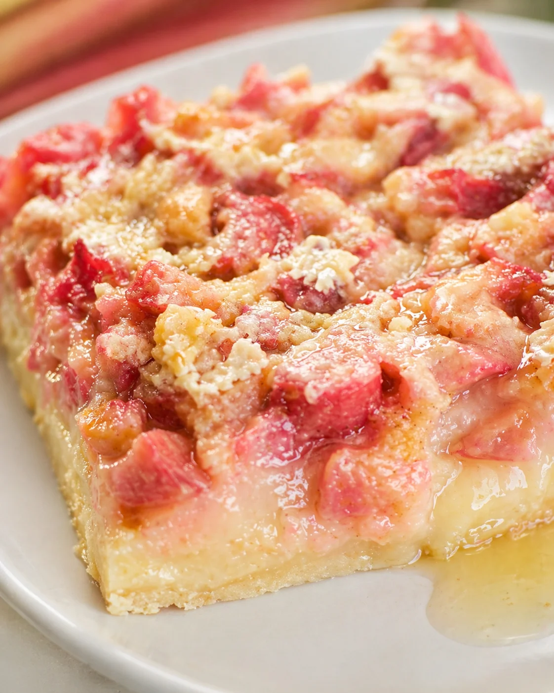 Close-up of a pink fruit bar slice with crumb topping on a white plate