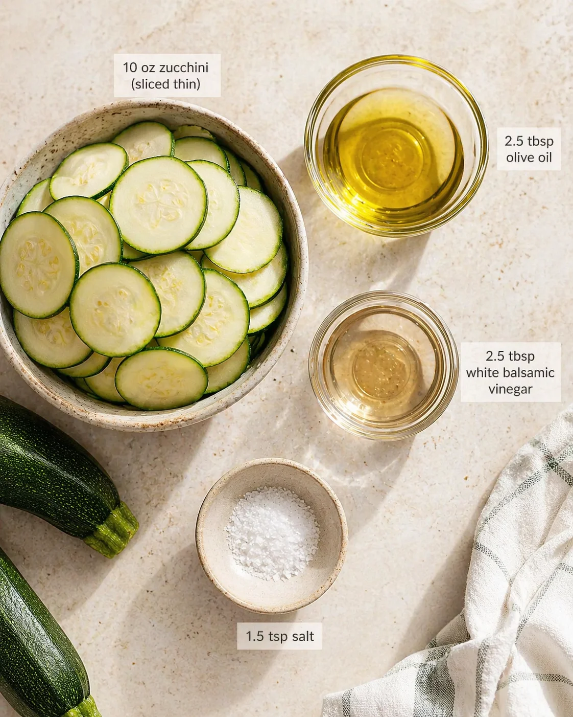 Overhead shot of sliced zucchini in a ceramic bowl with olive oil, vinegar, and salt