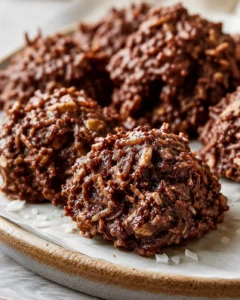 Close-up of glossy chocolate-coated rice cereal clusters on parchment-lined baking sheet.